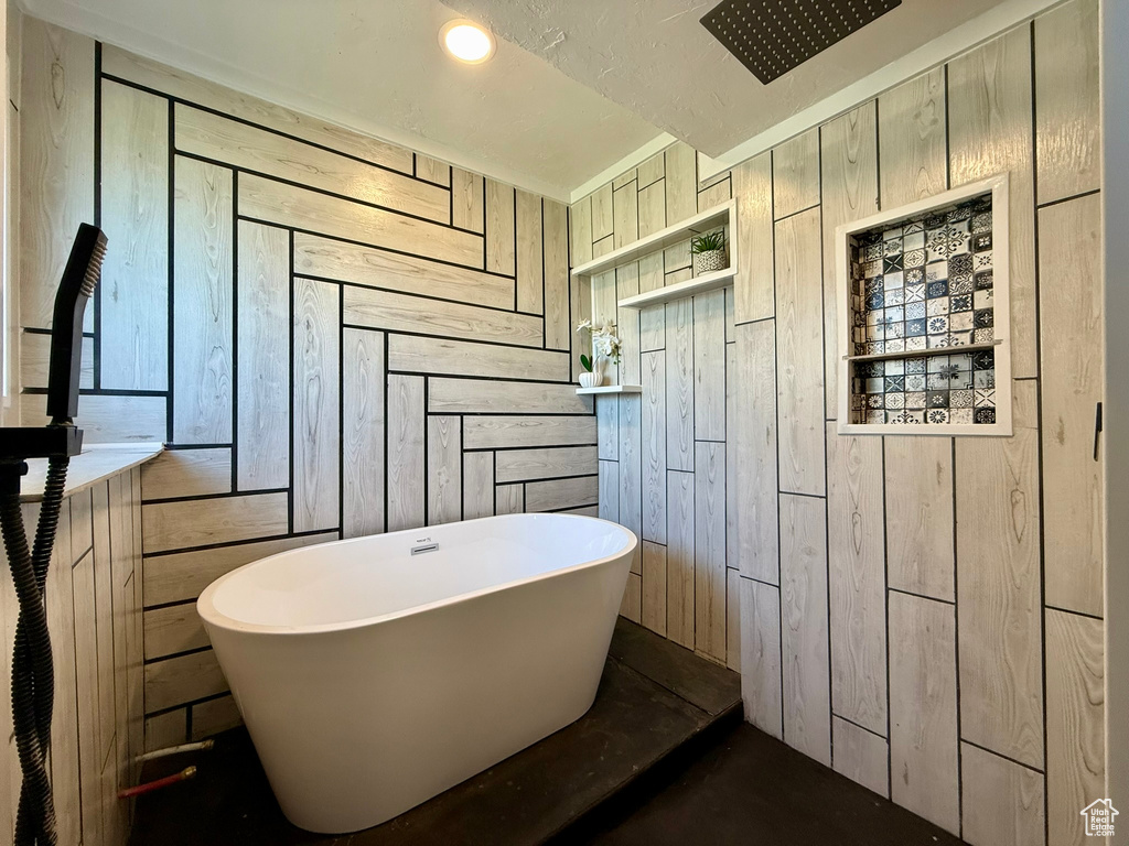 Bathroom featuring wood walls and a freestanding tub