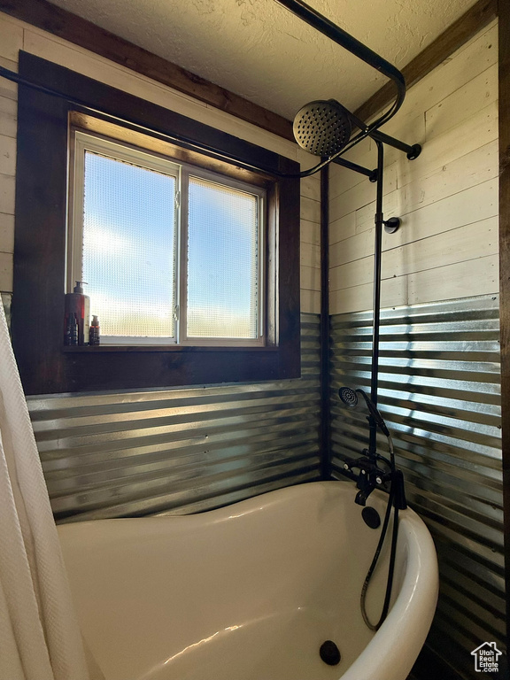 Full bath featuring wood walls and a textured ceiling