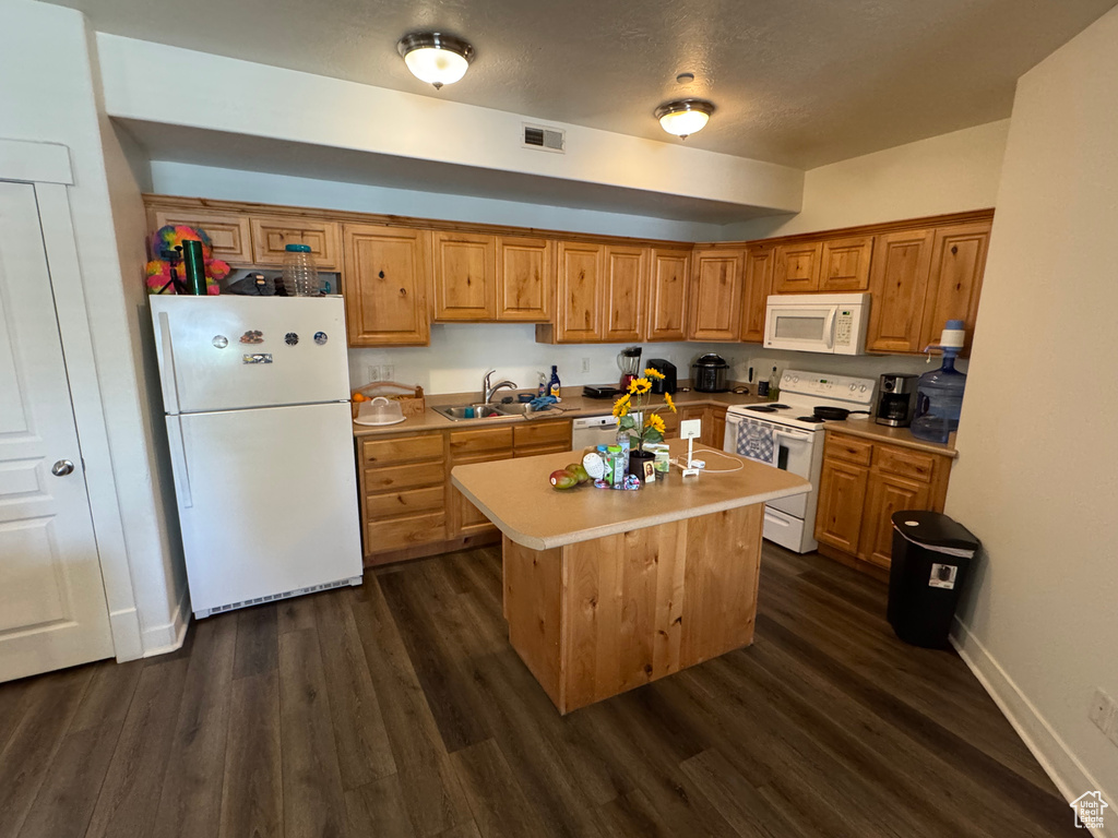 Kitchen featuring visible vents, a sink, dark wood-style flooring, and white appliances