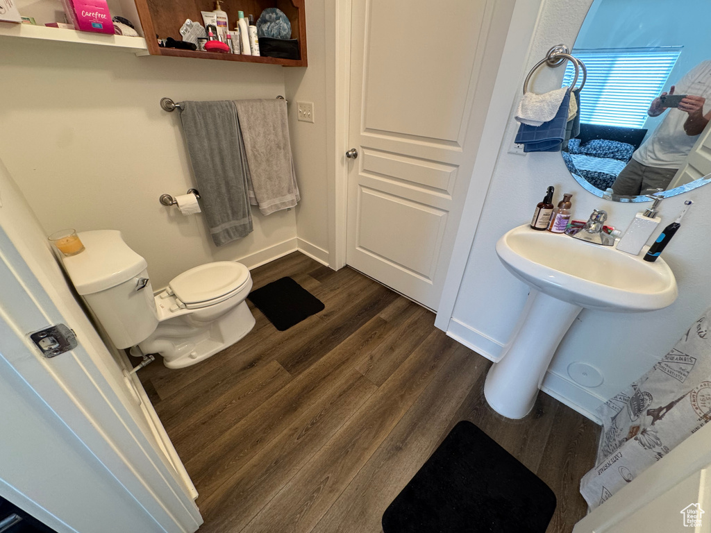Bathroom with toilet, baseboards, and wood finished floors