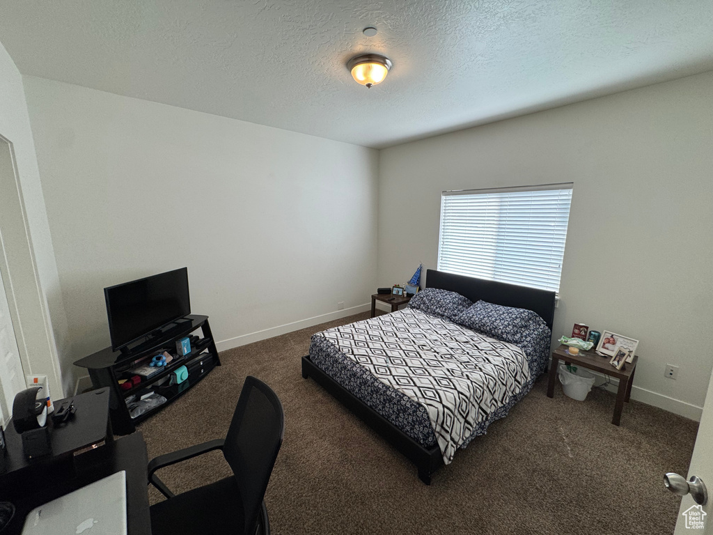 Bedroom with a textured ceiling, baseboards, and carpet
