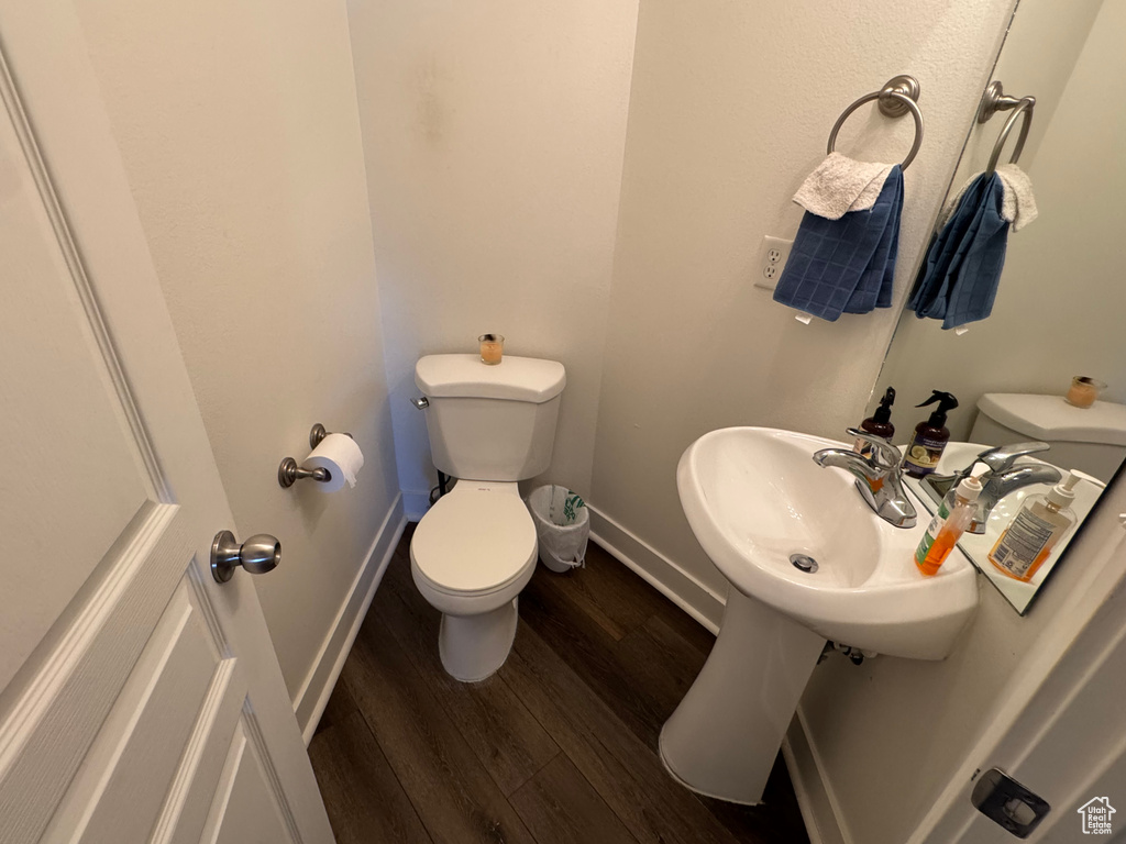 Bathroom with toilet, baseboards, a sink, and wood finished floors