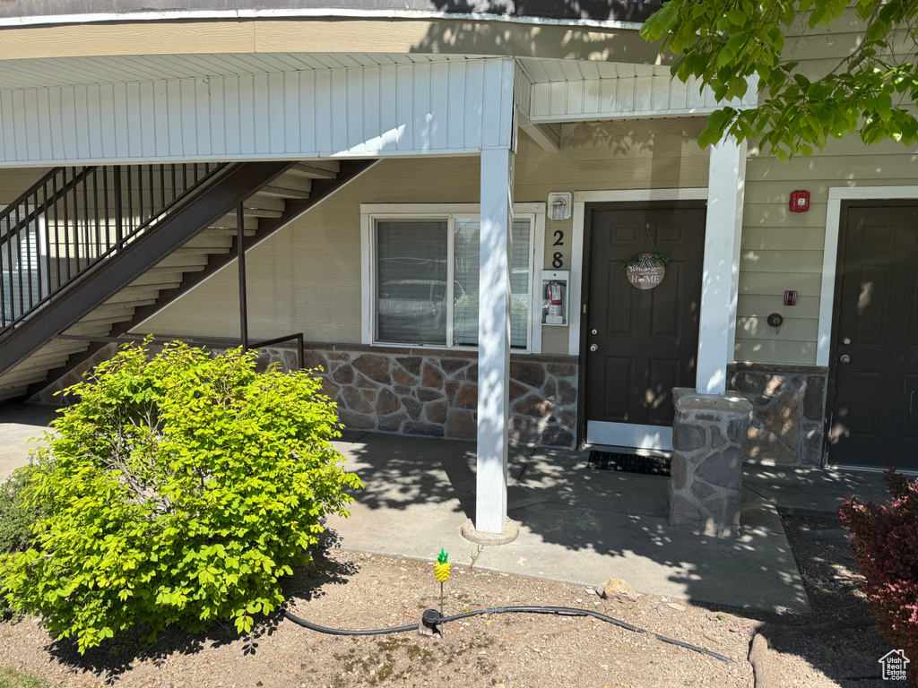 Doorway to property with covered porch and stone siding