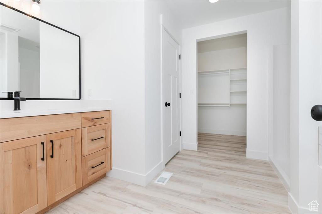 Bathroom featuring baseboards, vanity, wood finished floors, and visible vents