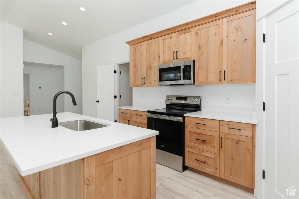 Kitchen featuring vaulted ceiling, recessed lighting, appliances with stainless steel finishes, a sink, and light brown cabinetry