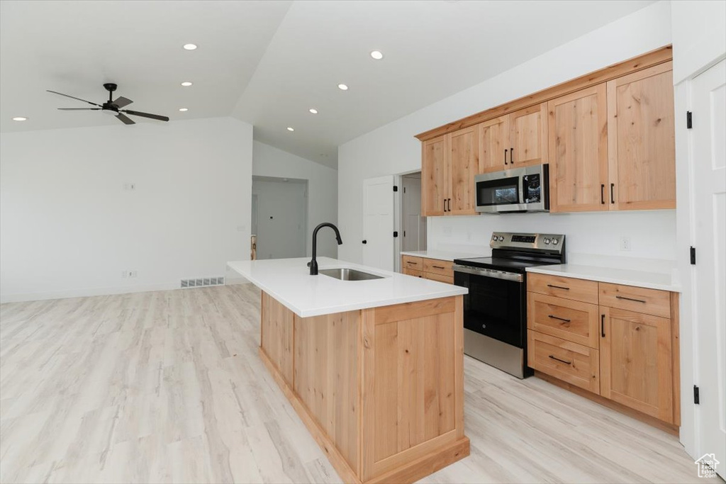 Kitchen featuring a sink, ceiling fan, appliances with stainless steel finishes, light wood-style floors, and vaulted ceiling