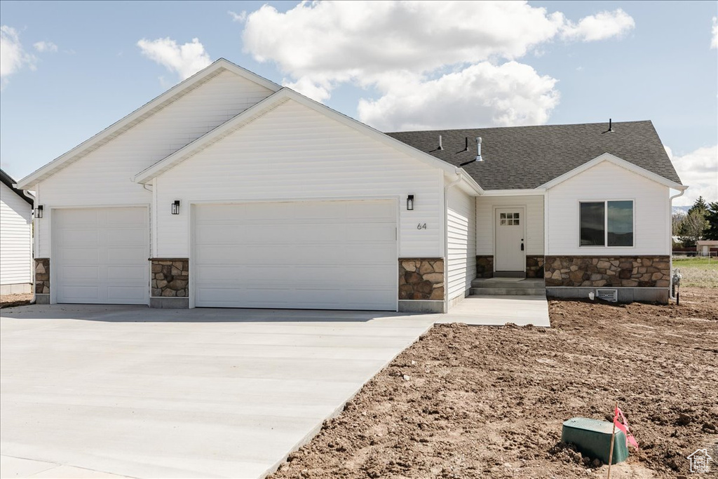 View of front of home with roof with shingles, driveway, stone siding, and a garage