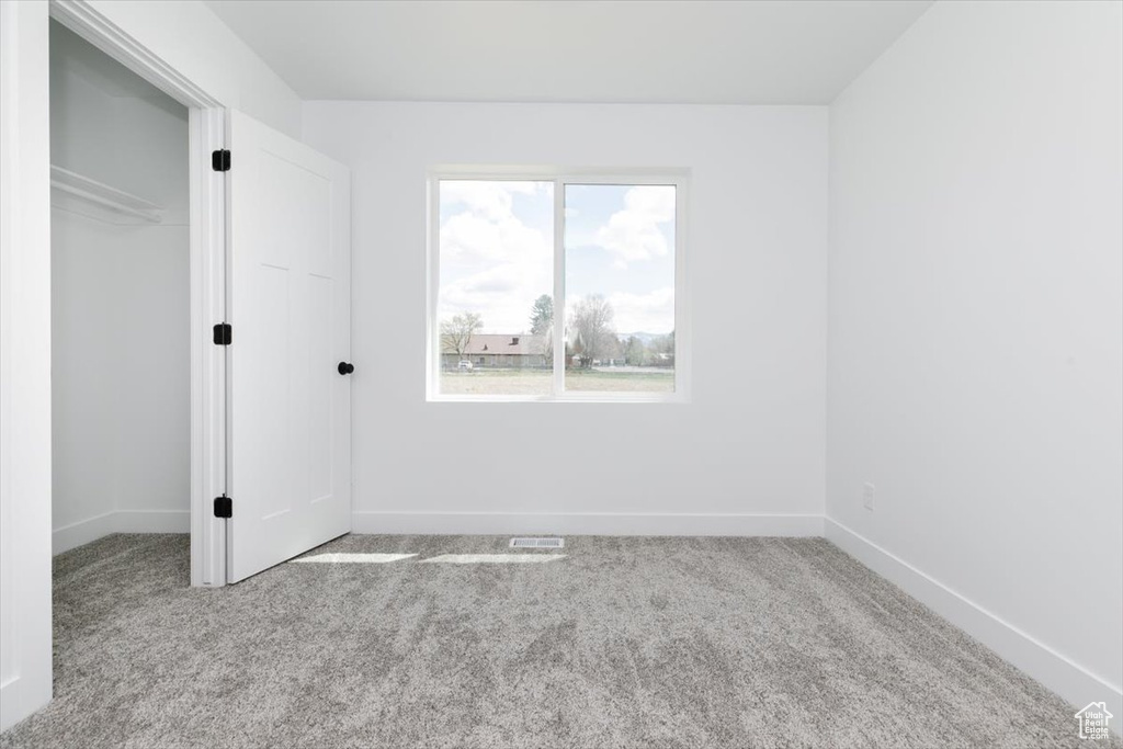 Unfurnished bedroom with baseboards, carpet flooring, visible vents, and a closet