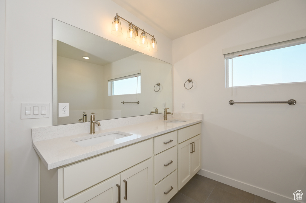 Bathroom with tile patterned floors, double vanity, a sink, and baseboards