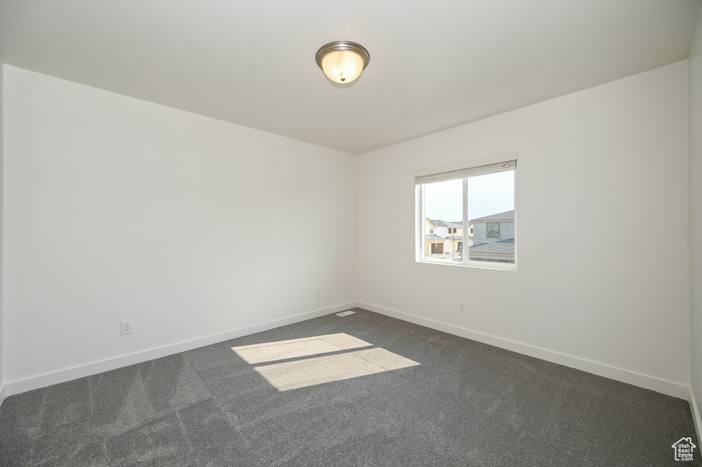Spare room with dark colored carpet and baseboards