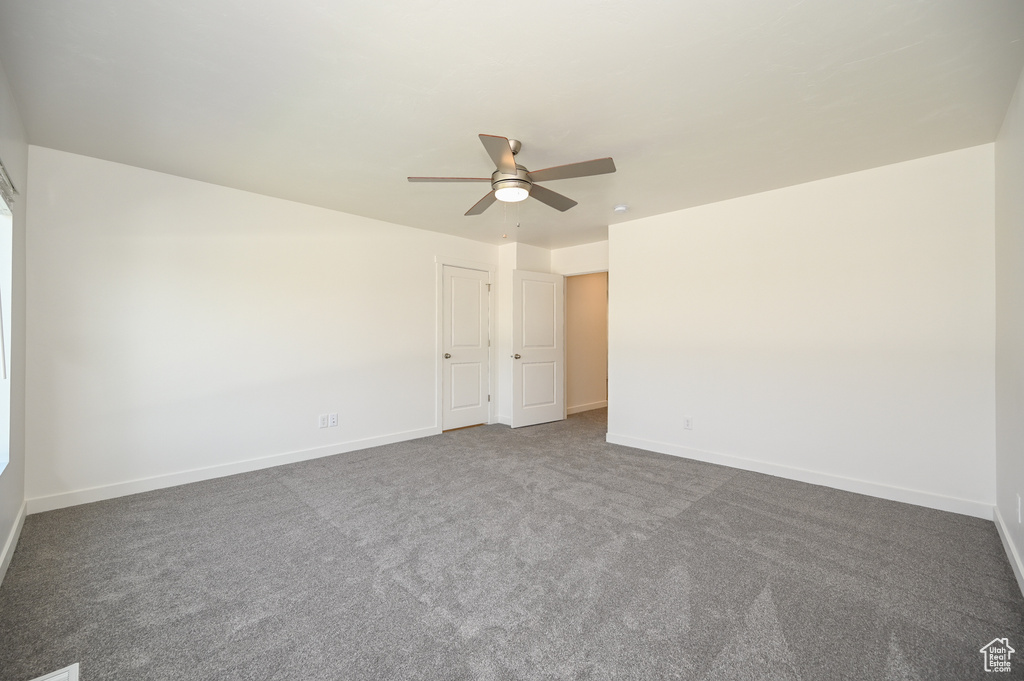 Carpeted empty room with ceiling fan and baseboards