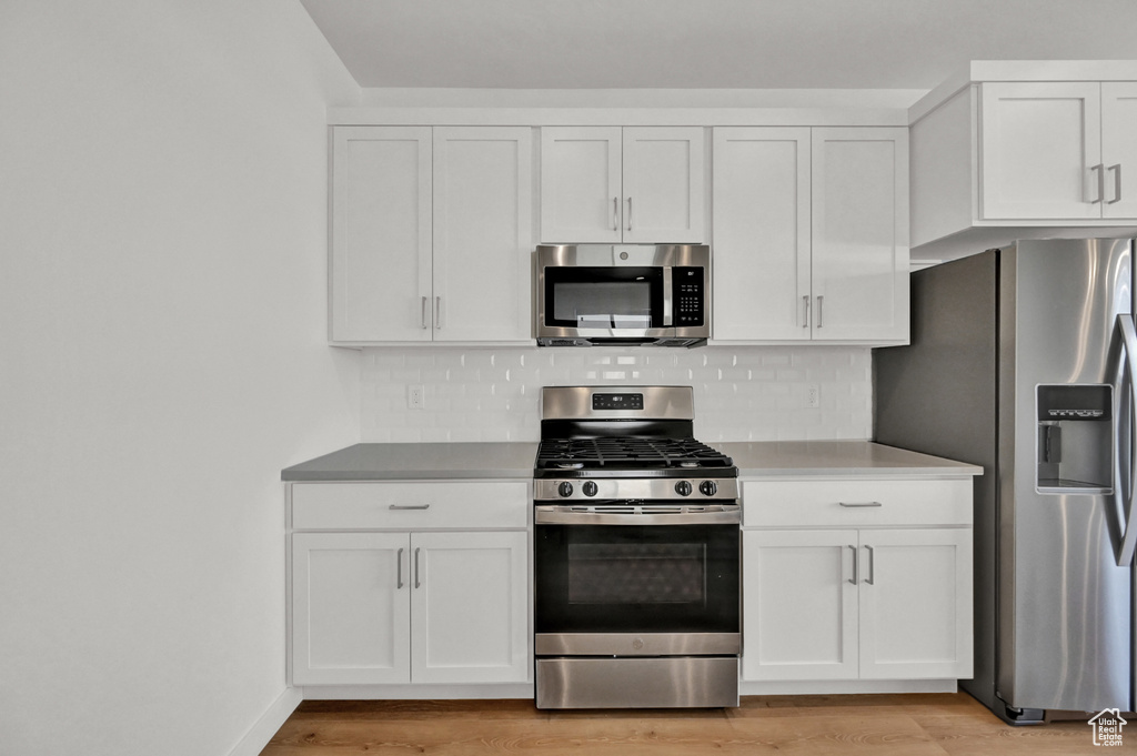 Kitchen with light wood-style flooring, white cabinetry, and stainless steel appliances