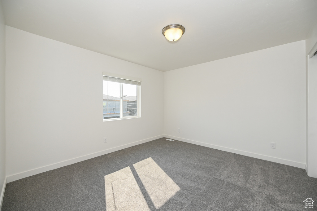 Spare room with dark colored carpet and baseboards