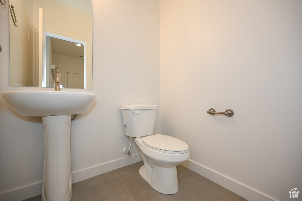 Half bathroom with toilet, baseboards, and tile patterned flooring