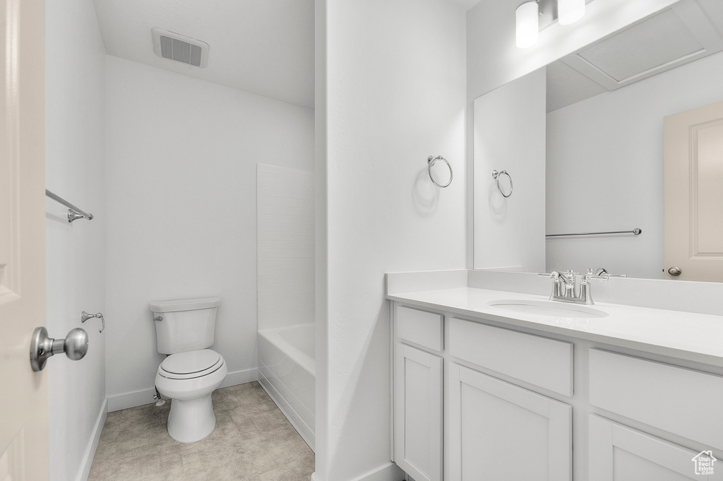 Bathroom with toilet, vanity, and baseboards