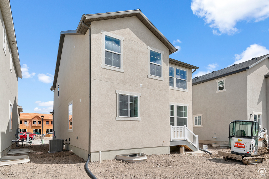 Rear view of house with stucco siding and central AC