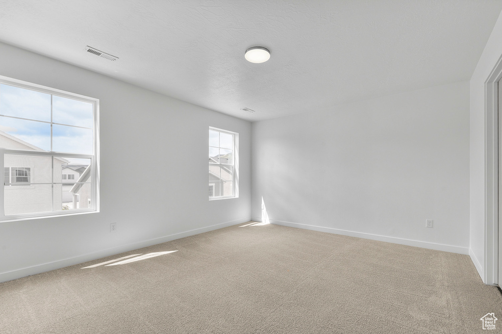 Unfurnished room featuring light carpet and baseboards