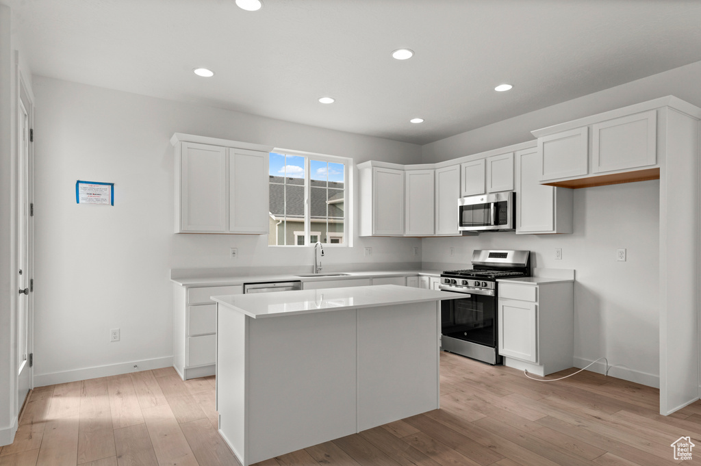 Kitchen featuring appliances with stainless steel finishes, a sink, baseboards, light wood-style flooring, and recessed lighting