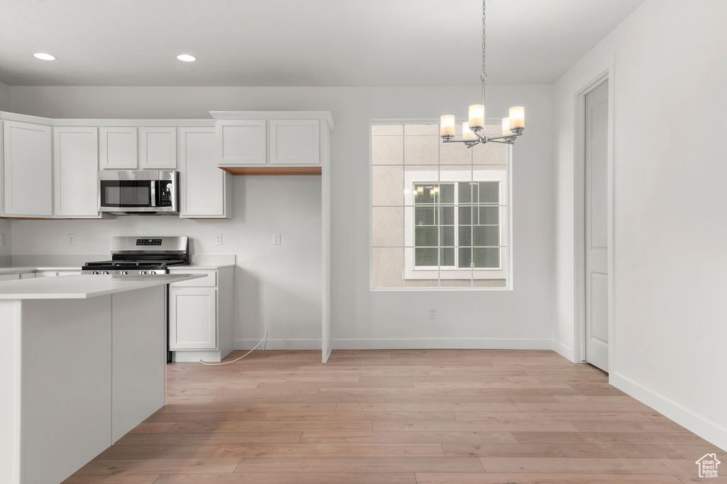 Kitchen featuring stainless steel appliances, a chandelier, baseboards, light countertops, and recessed lighting