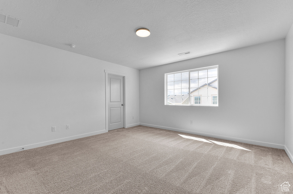 Spare room with carpet floors, baseboards, and a textured ceiling