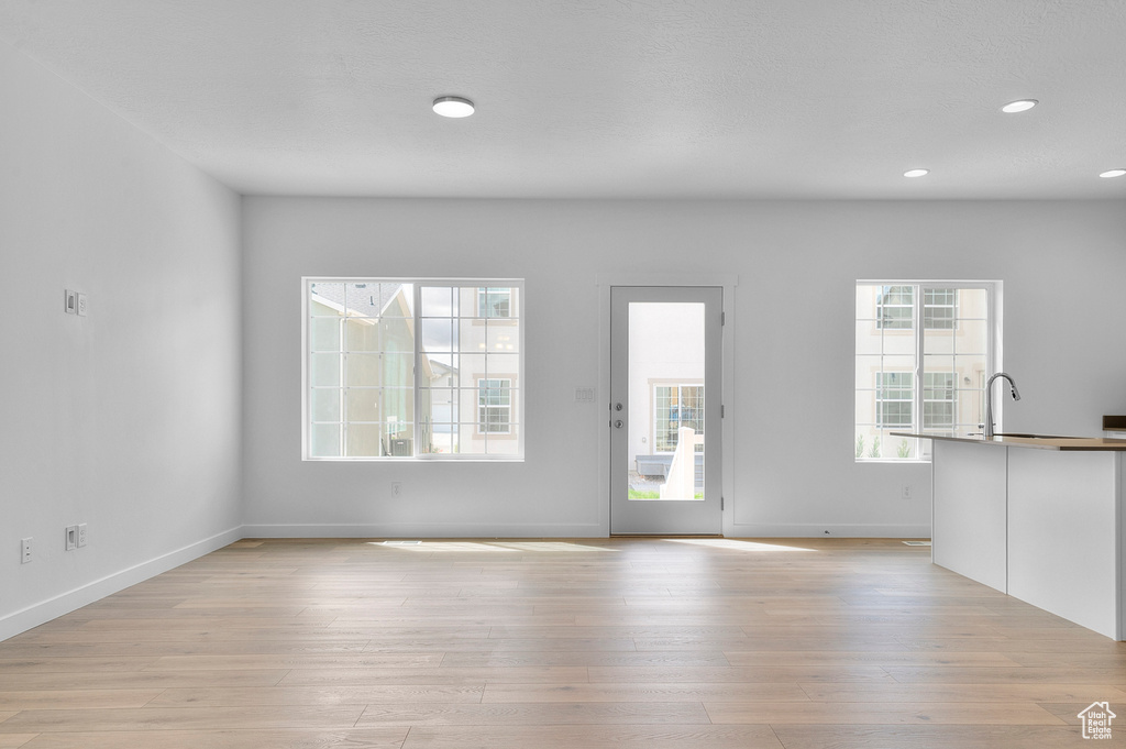 Unfurnished living room featuring light wood-type flooring, baseboards, and recessed lighting