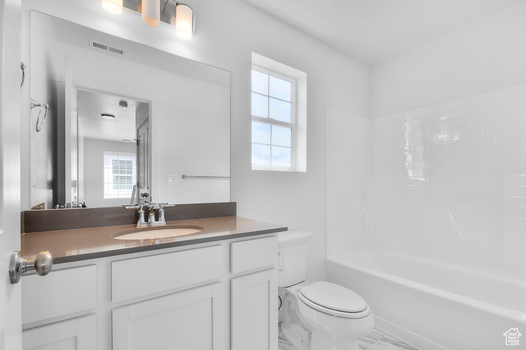 Bathroom featuring plenty of natural light, toilet, marble finish floors, and vanity