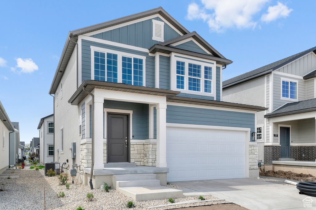 View of front facade with central AC unit, driveway, and a garage