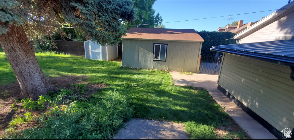 View of yard featuring a shed, an outdoor structure, fence, and a gate