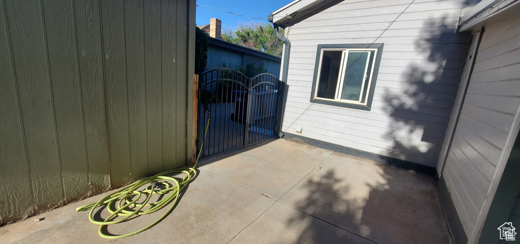 View of side of home featuring fence, a patio, and a gate
