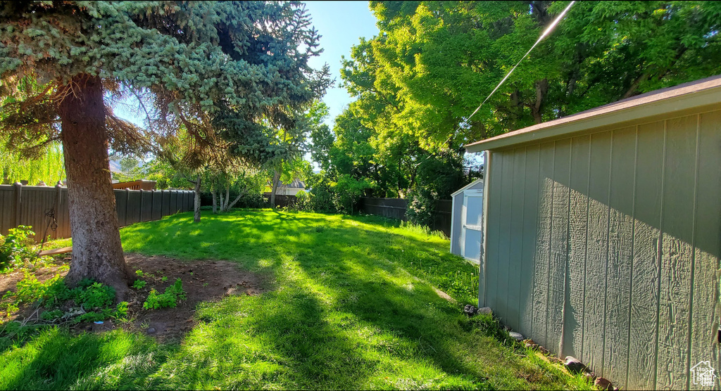 View of yard featuring a fenced backyard, a storage shed, and an outbuilding