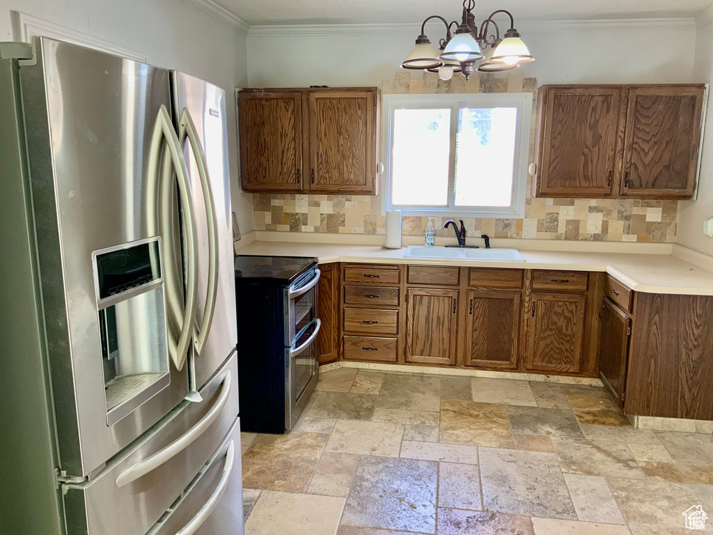 Kitchen featuring a notable chandelier, a sink, appliances with stainless steel finishes, brown cabinets, and backsplash