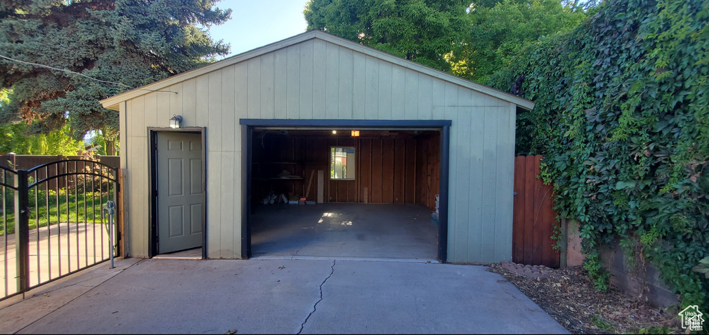 Detached garage with concrete driveway, fence, and a gate