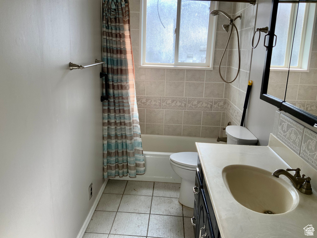 Full bathroom featuring shower / bath combination with curtain, vanity, tile patterned flooring, toilet, and baseboards