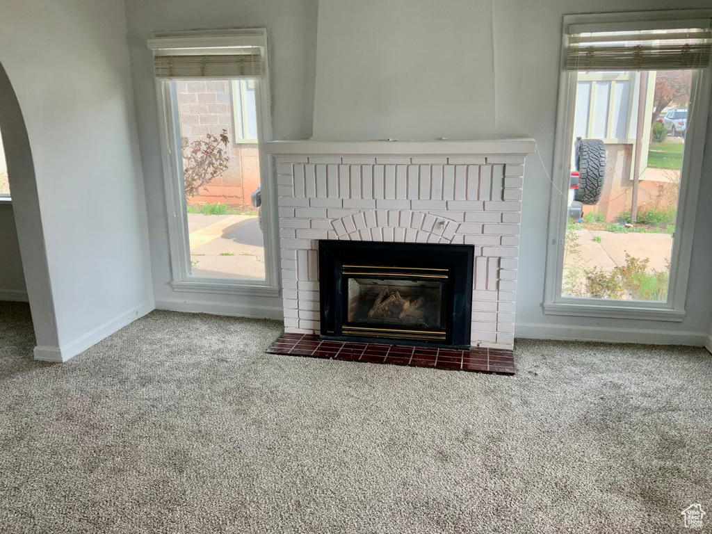 Interior details with arched walkways, baseboards, carpet, and a brick fireplace
