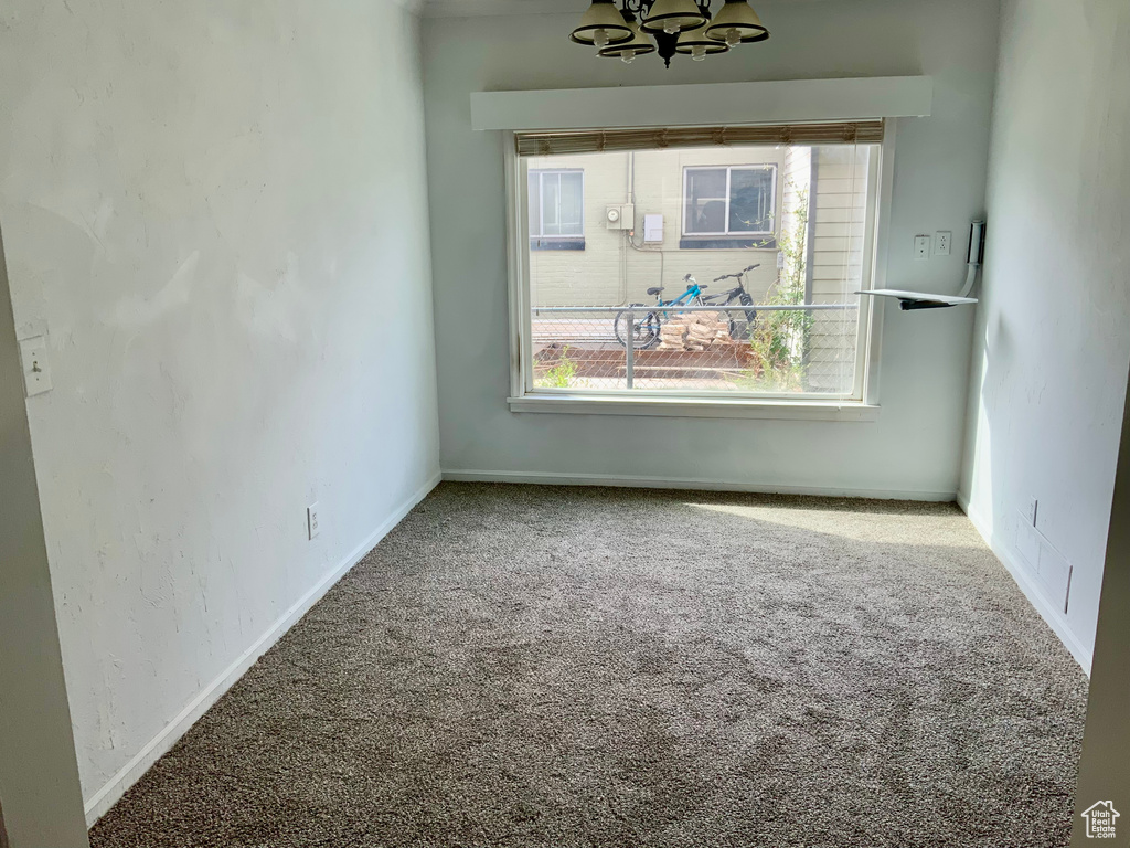 Unfurnished dining area with a notable chandelier, baseboards, and carpet floors