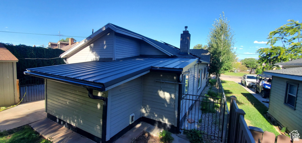 Exterior space featuring a chimney, metal roof, fence, and a yard
