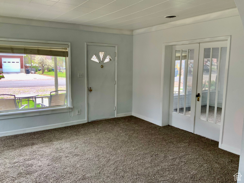 Carpeted foyer with crown molding, french doors, baseboards, and visible vents