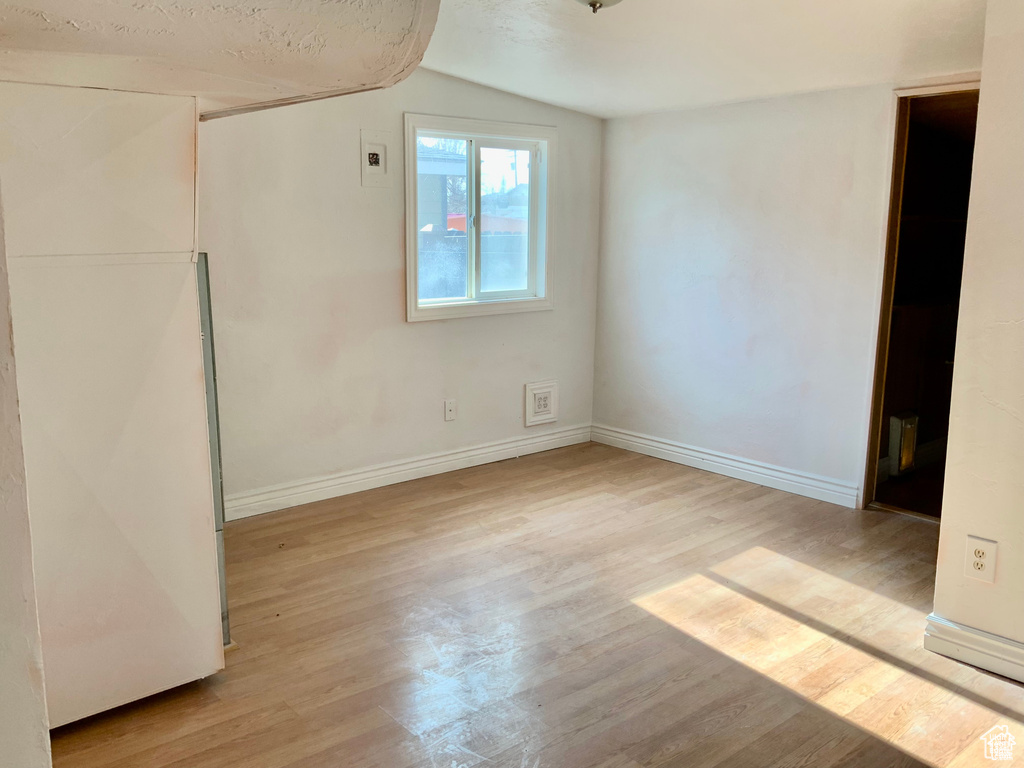 Unfurnished bedroom featuring baseboards, wood finished floors, and lofted ceiling