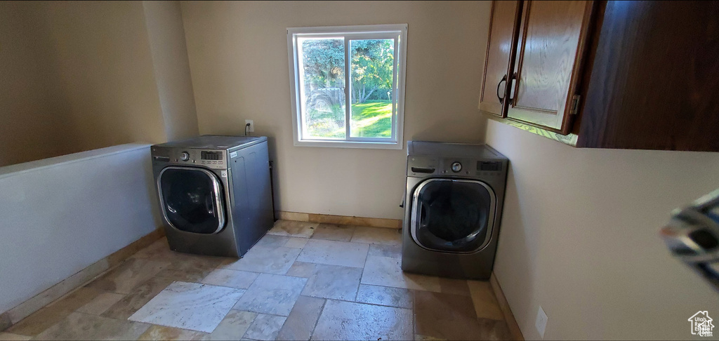 Washroom with stone tile floors, washer / dryer, baseboards, and cabinet space