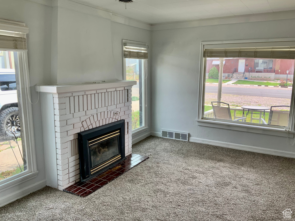 Unfurnished living room with carpet flooring, baseboards, visible vents, and a fireplace