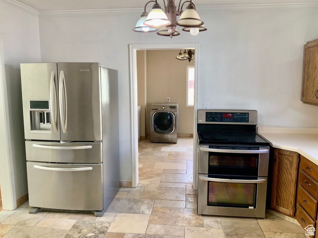 Kitchen with washer / clothes dryer, a chandelier, brown cabinets, appliances with stainless steel finishes, and stone tile floors