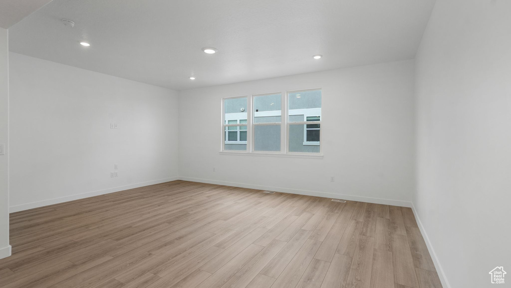 Empty room with light wood-style floors and recessed lighting
