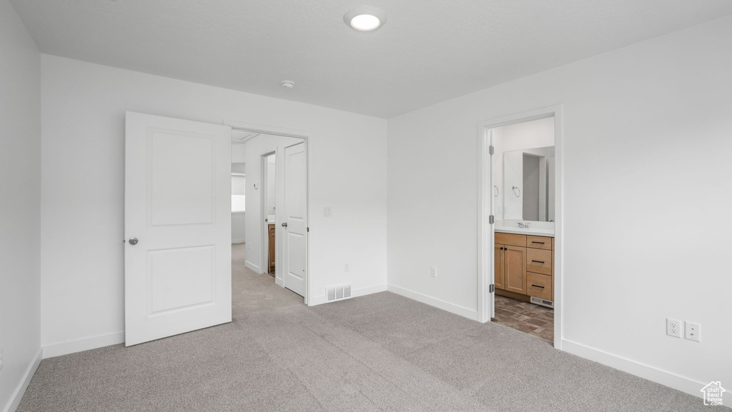 Unfurnished bedroom with carpet floors and ensuite bath