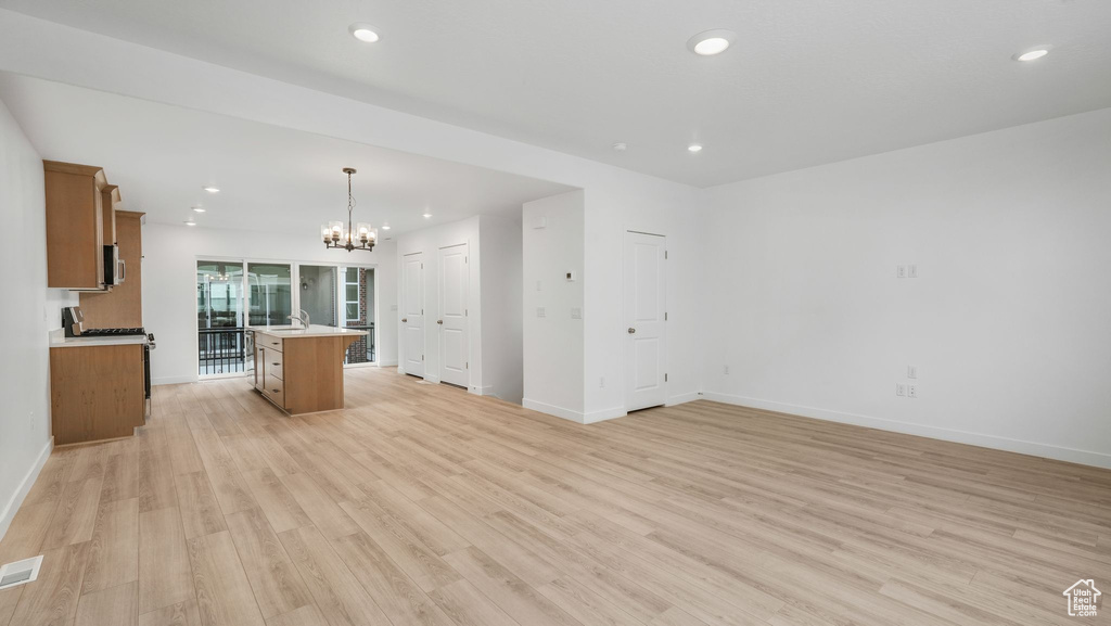 Unfurnished living room with a chandelier, light wood-style flooring, and recessed lighting
