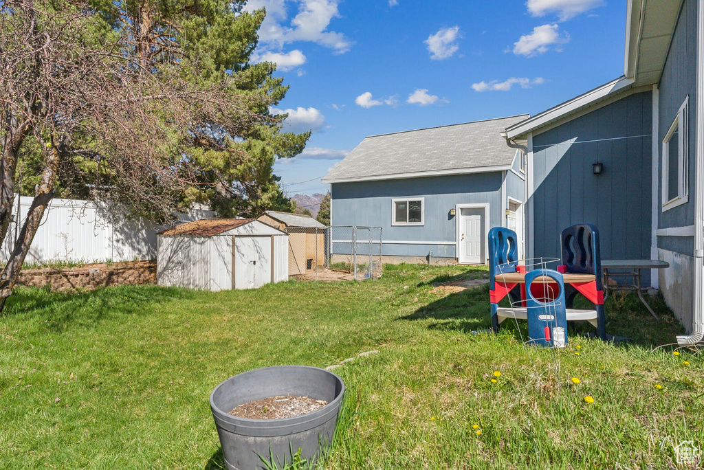 View of yard with an outdoor structure, fence, and a storage unit