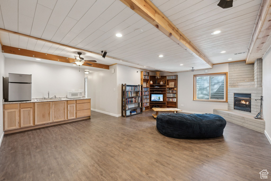 Living room featuring wood finished floors, baseboards, and a brick fireplace