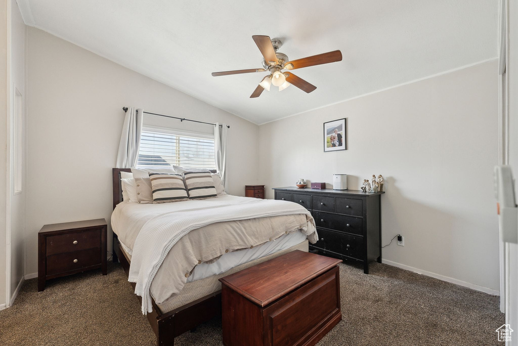 Carpeted bedroom with baseboards, vaulted ceiling, and ceiling fan