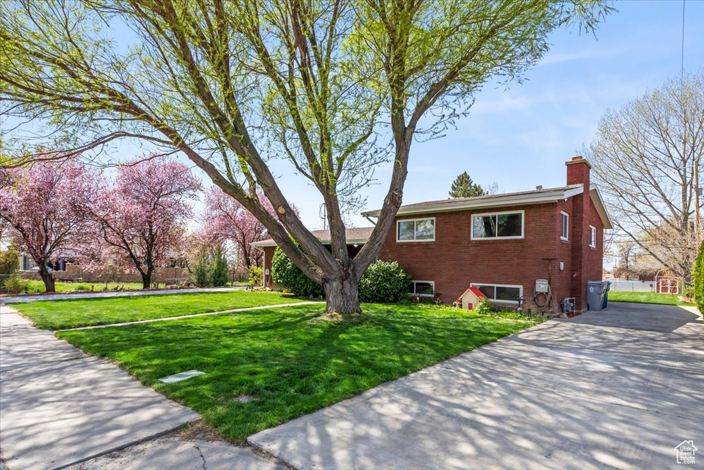 View of property exterior featuring a chimney, brick siding, and a lawn
