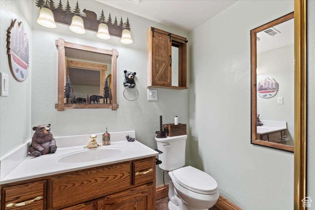 Half bathroom with vanity, visible vents, and toilet