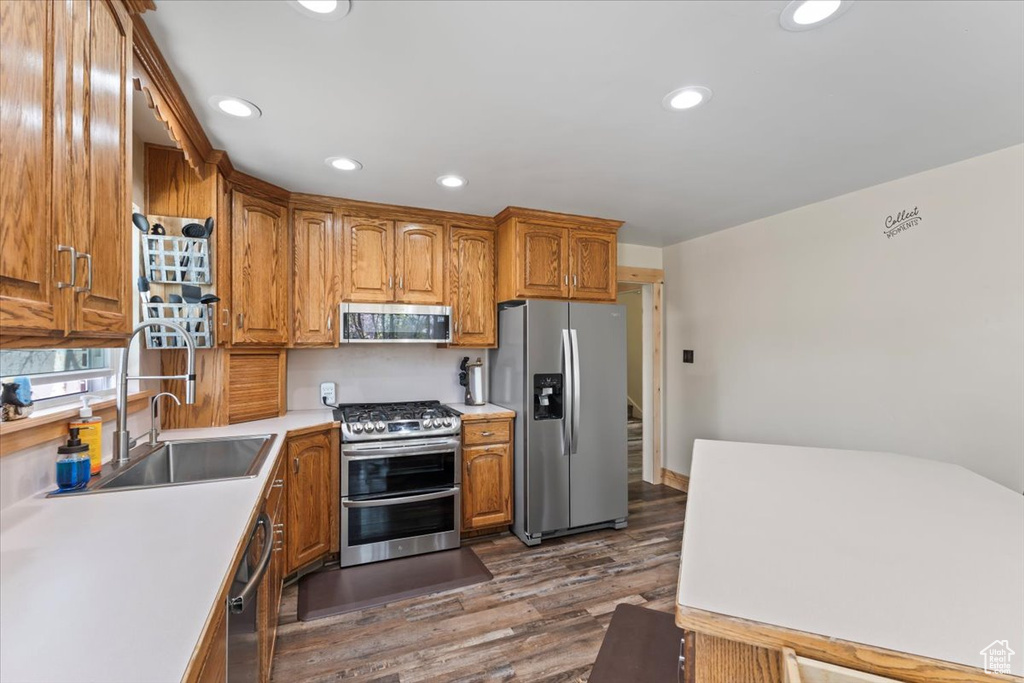 Kitchen with recessed lighting, dark wood-style floors, light countertops, brown cabinetry, and stainless steel appliances